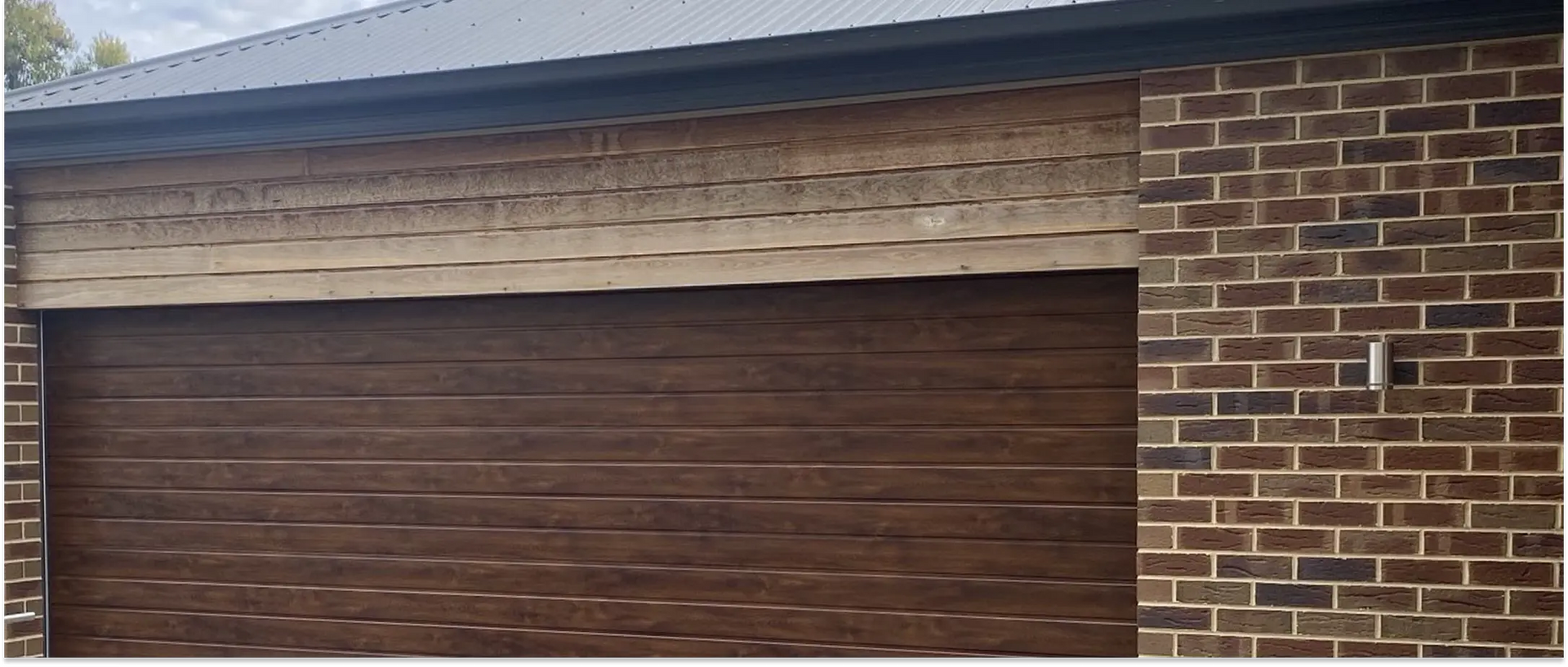 Black roll-up shutter on a brick building with a protruding frame.